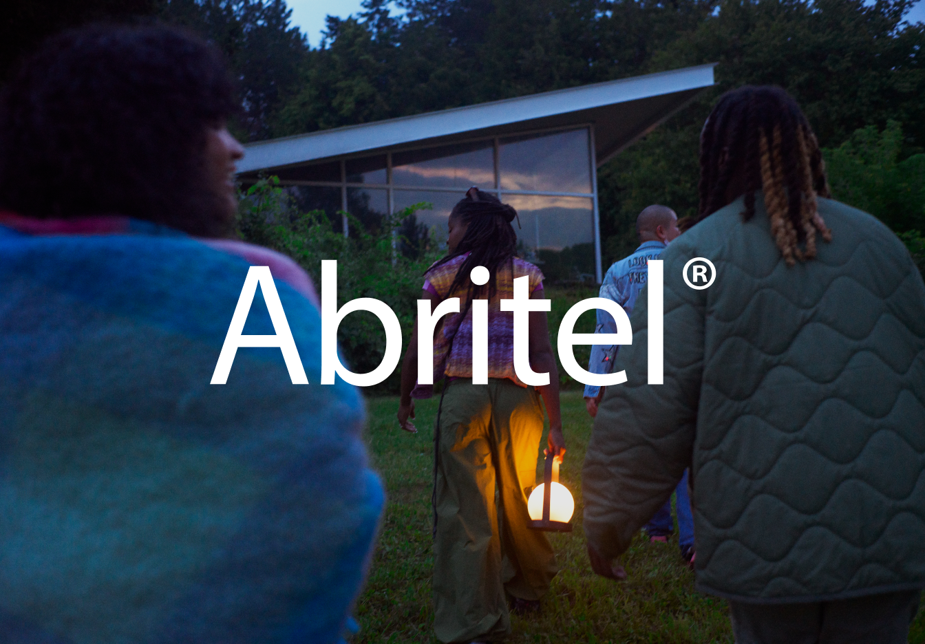 Quelques personnes, l’une d’elles tenant une lanterne, marchent vers une maison. Le logo Vrbo est affiché en surimpression.