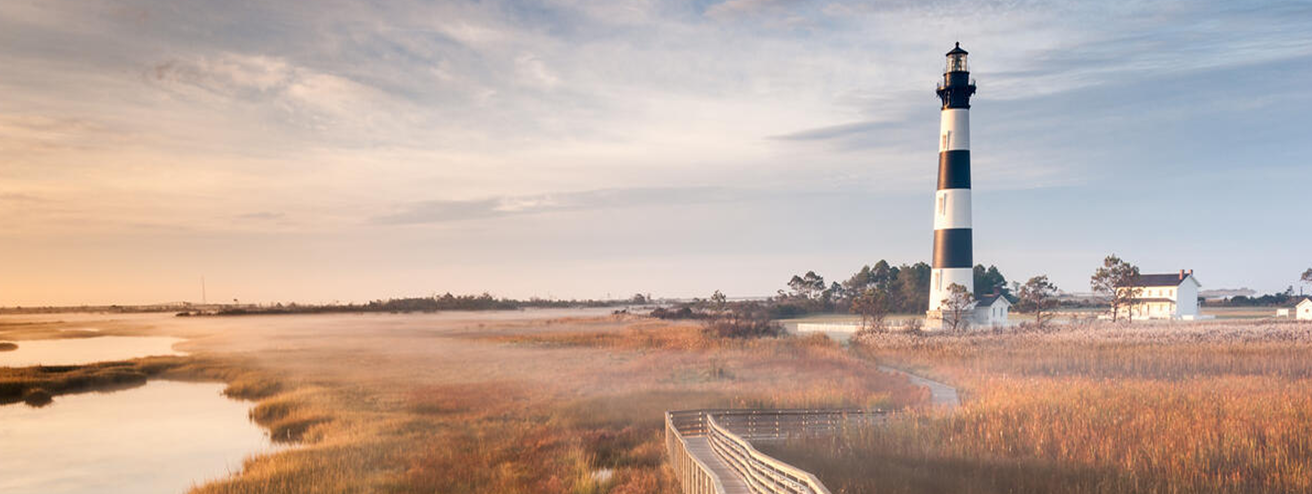 A beautiful landscape picture of a lighthouse on a field with a lake