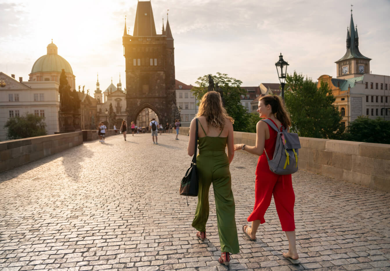 Two friends chat while walking on Charles Bridge in Prague, Czech Republic.