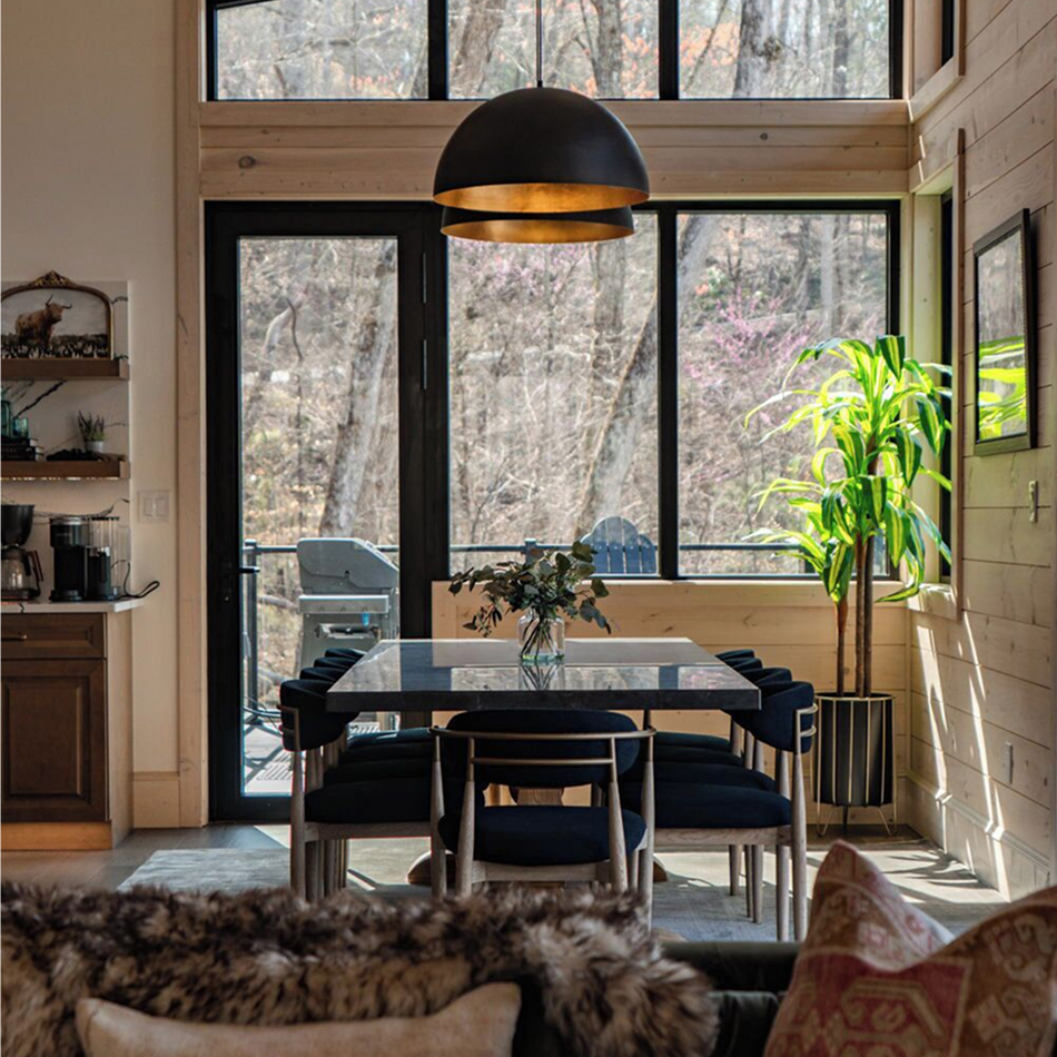 Cozy dining area with large windows, black chairs, and view of trees outside