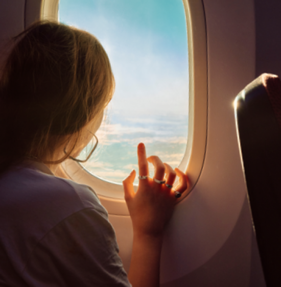 A woman starting out of the window of an airplane mid-flight