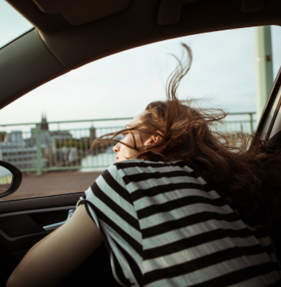 A woman sitting in the passenger seat of a car with her head leaning out of the window