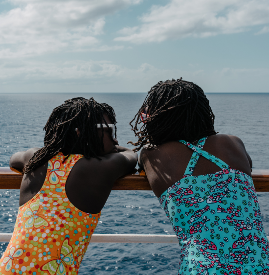 Two children leaning against the guardrails of a cruise ship