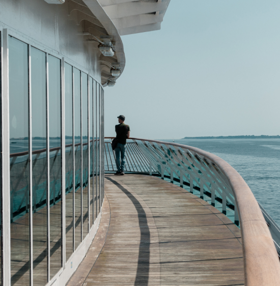 A man standing alone at the bow of a ship on the ocean