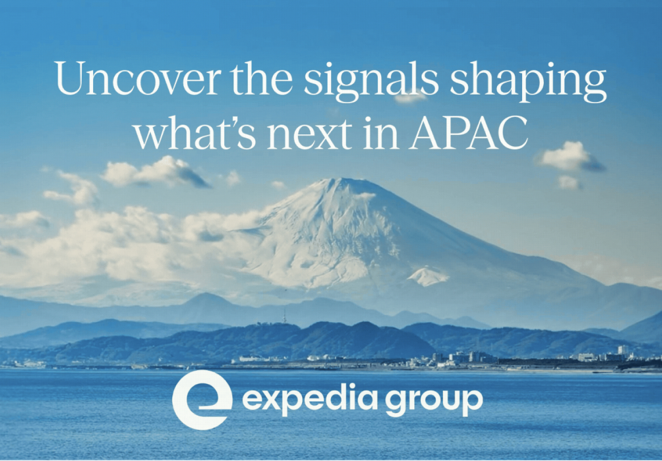Wide landscape view of a snow-capped mountain rising in the distance beyond calm blue water, with low shoreline hills at the base, soft white clouds across the middle of the scene, and a clear bright blue sky overhead. Overlaid with the headline “Uncover the signals shaping what’s next in APAC” and the Expedia Group logo at the bottom.