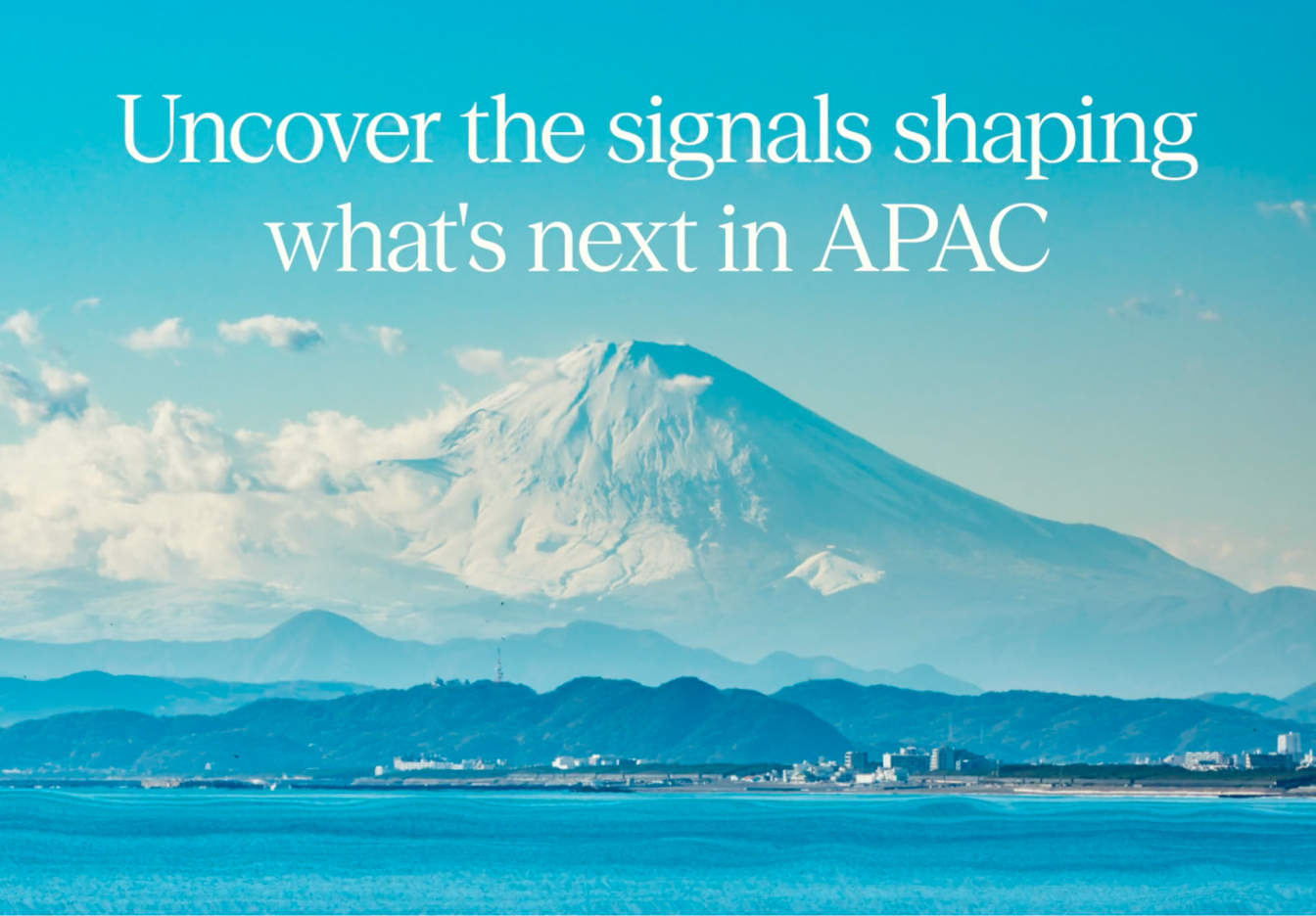 Wide landscape view of a snow-capped mountain rising in the distance beyond calm blue water, with low shoreline hills at the base, soft white clouds across the middle of the scene and a clear bright blue sky overhead. Overlaid with the headline "Uncover the signals shaping what's next in APAC" and the Expedia Group logo at the bottom.