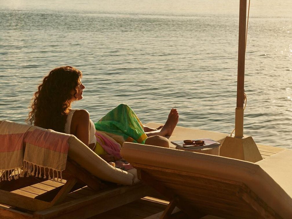 Woman lounging by the water at sunset.