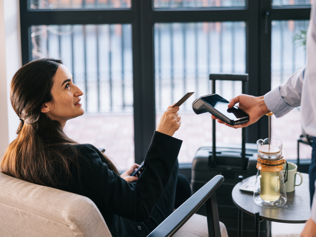 A young woman using her card to pay using contact-less