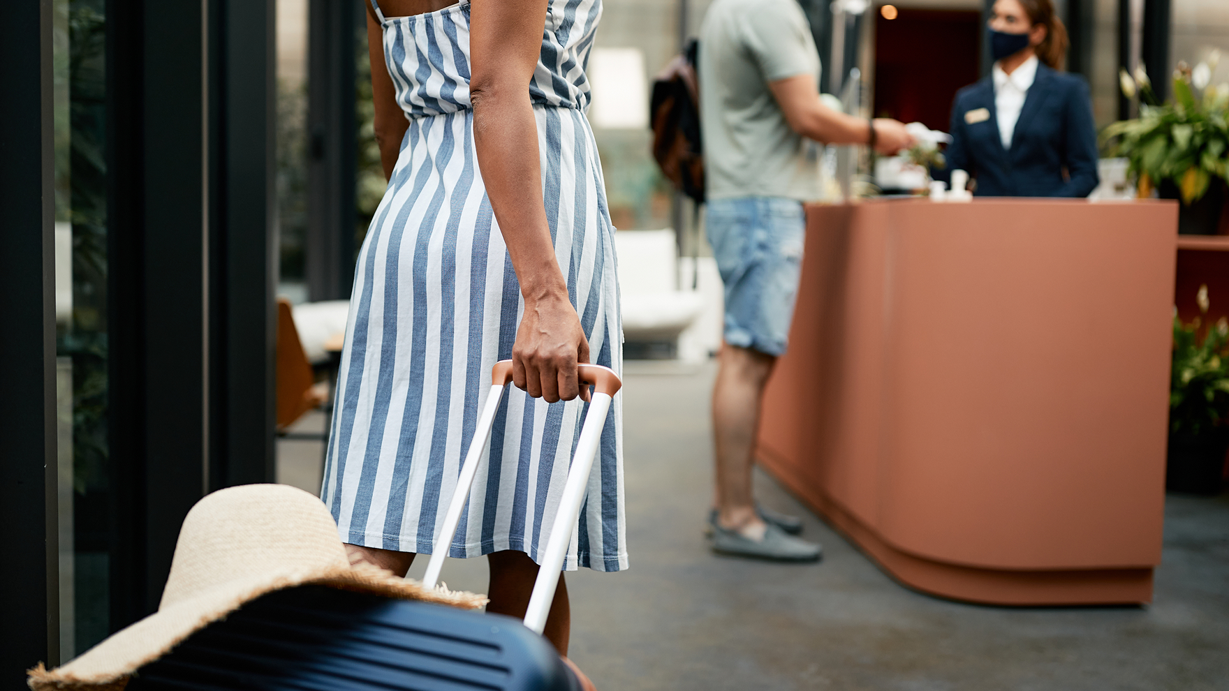 Photo of a woman carrying a suitcase through a hotel lobby.
