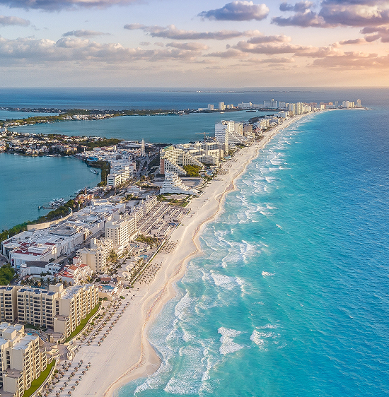 Aerial view of a beach with turquoise ocean, sandy shore, and resort buildings.