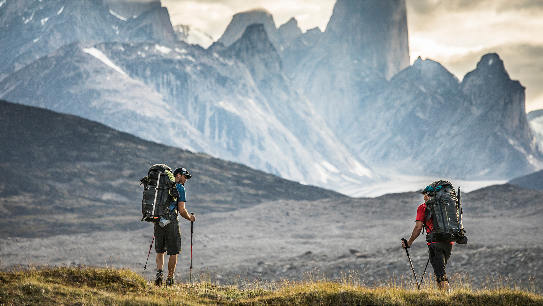 Two climbers hike toward mount asgard in akshayak pass, baffin island.