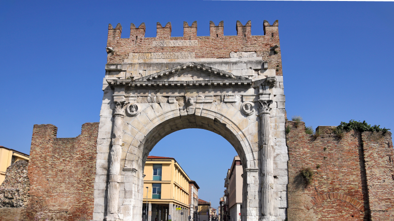 View of a small European-style town square, seen through the remains of the Arch of Augustus, a triumphal gate in Rimini, Italy.