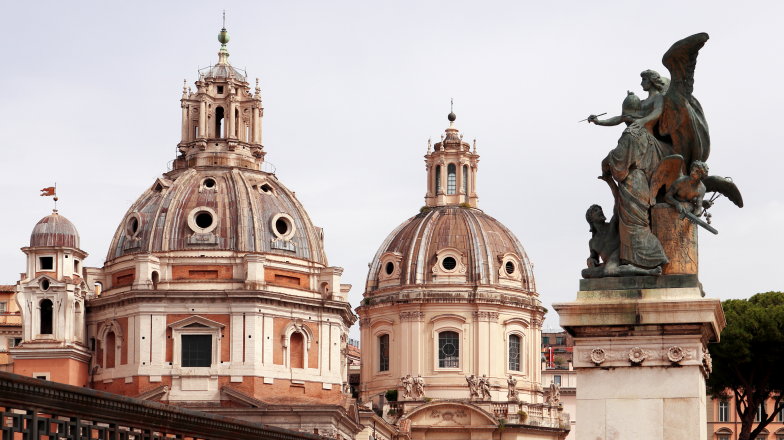 View of the domes of two churches in Piazza Venezia, in Rome with a statue of angels in the foreground.