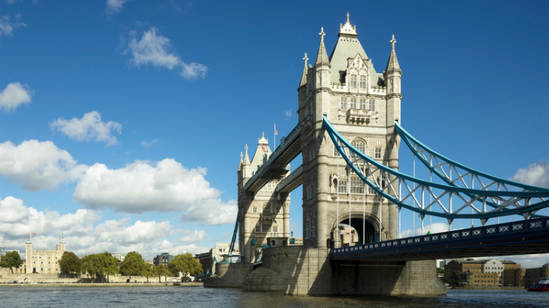 Bright, daytime view of the Tower Bridge in London spanning the Thames River.