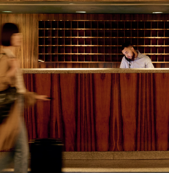 A hotel guest checks in at a contemporary wooden front desk.
