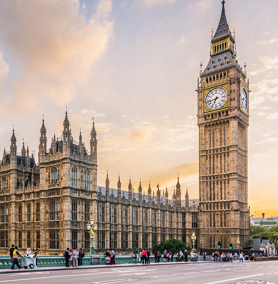 Iconic view of the Elizabeth Tower, commonly known as Big Ben, and the Houses of Parliament alongside the River Thames in London under a partly cloudy sky.