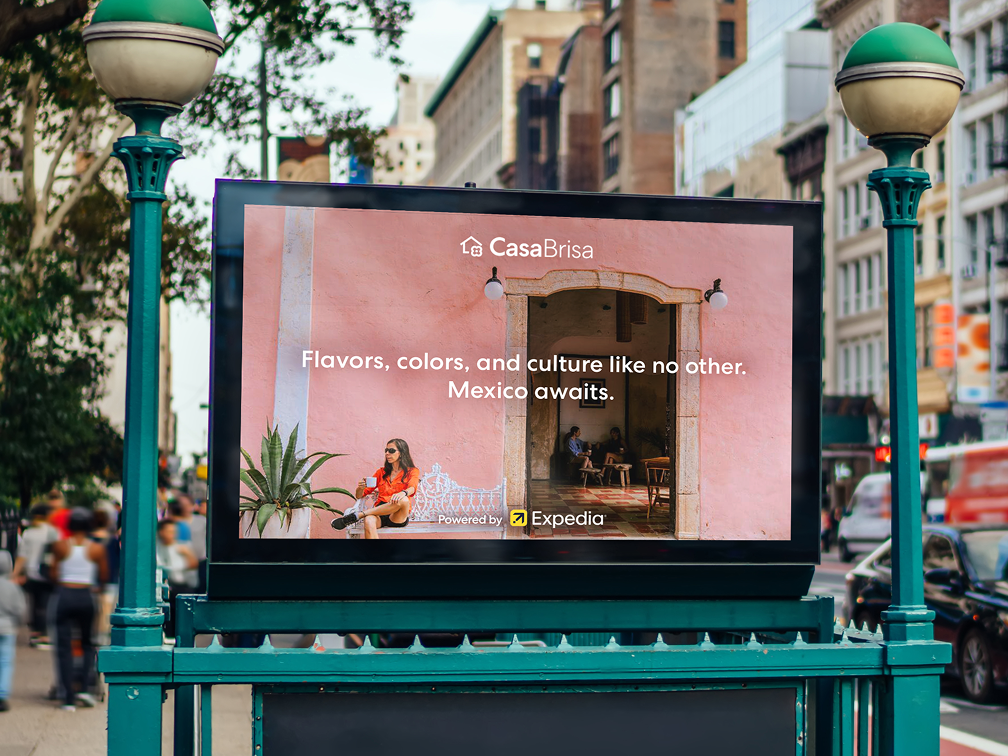 Offsite Expedia advertisement on a digital screen on a public city street by CasaBrisa with text saying "Flavors, colors, and culture like no other. Mexico awaits. Powered by Expedia".