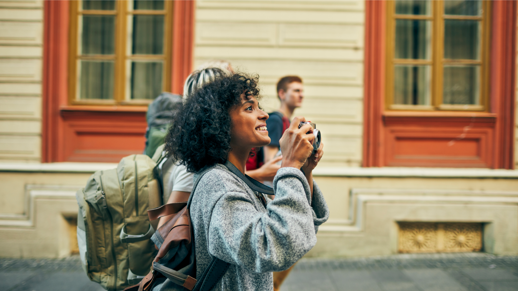 Woman holding camera tours a city with friends.