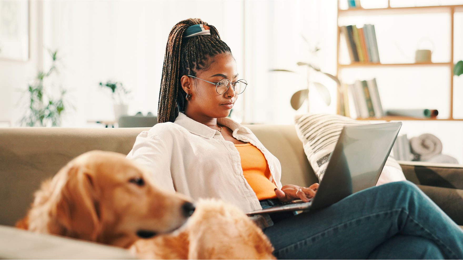  An image of a Woman looking at her laptop sitting on a couch with dog